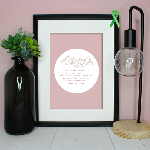 Blush pink print in a frame with a mountain outline illustration and a quote about living life